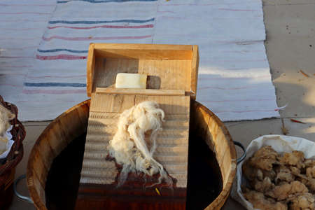 A wooden washboard, a bar of soap and sheep's wool in a wooden basin of water. hand washing clothing.の写真素材