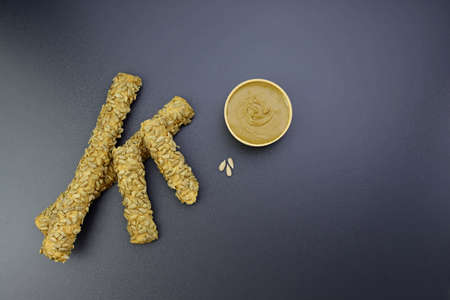 Bread sticks and sunflower seed paste on a gray background.の写真素材