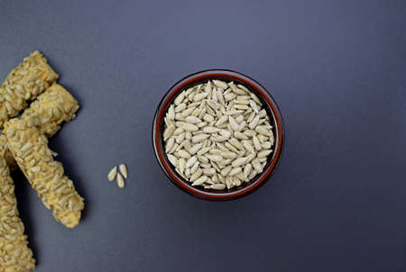 Peeled sunflower seeds in a round bowl on a gray background.の写真素材