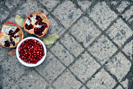 Peeled red pomegranate seeds and ripe pomegranate halves on a stony gray background.の写真素材