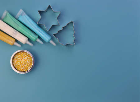 Colored sugar decoration and steel cookie cutters on a blue background. Tubes of paint and small pearlescent granules for decorating baked goods.の写真素材
