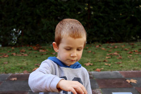 The blond boy looks at the toys with concentration. Four year old pensive boyの写真素材