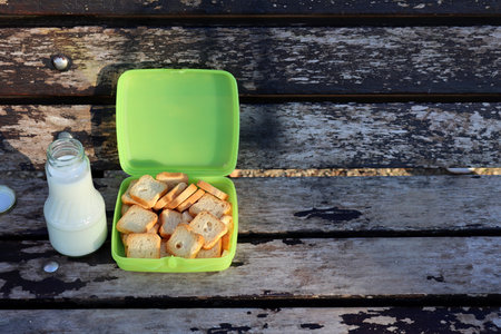 White bread croutons and milk on a wooden background. Toast in a plastic box and milk in a glass...
