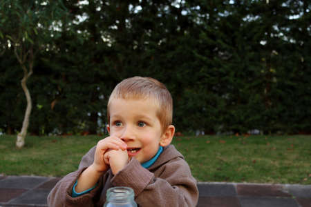 A blond boy with big eyes and an open mouth looks into the distance. Four year old boy with a surprised lookの写真素材