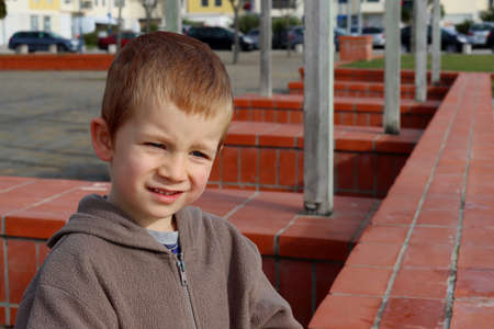 The blond boy bowed his head and looks into the distance with a smile. The four-year-old boy narrowed his eyes.の写真素材
