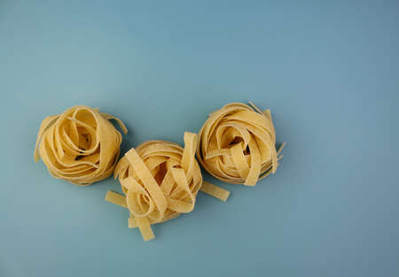 Tagliatelle pasta on a blue background. Yellow pasta tagliatelle from durum wheat.の写真素材