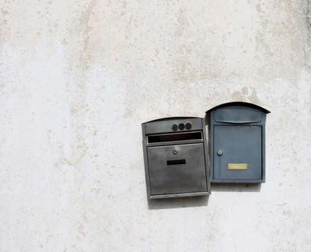 Two metal mailboxes hang on a light, dirty wall. old mailboxes.の写真素材