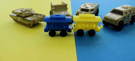 Blue and yellow train on the background of military equipment. Russian invasion of Ukraine. Ukraine is a free country.の写真素材