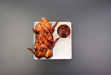 Baked chicken wings in a square plate on a gray background. Crispy chicken wings.の写真素材