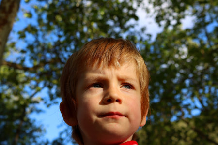 Portrait of a serious blond boy with dirty lips. A five-year-old boy looks into the distance with a frown.の写真素材