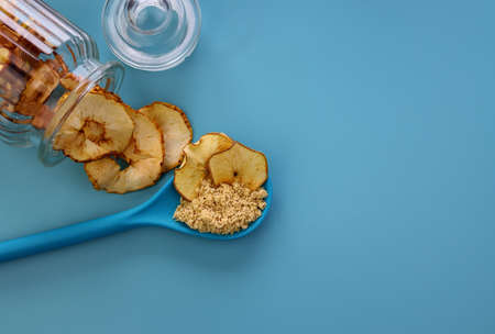 Dried apples and apple flour in a blue spoon on a blue background. Drying apples and apple pectin at home.の写真素材