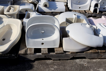 Ceramic sinks lie on wooden pallets on the street. The shells are turned upside down. ceramic...