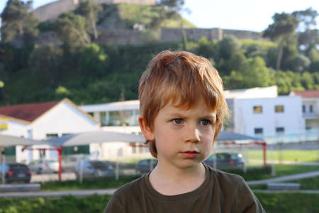 Serious blond boy looks into the distance. Thoughtful five year old boy.の写真素材