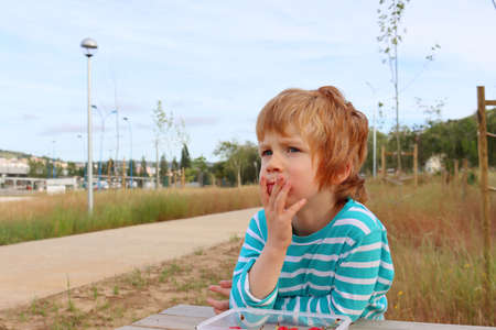 The blond boy holds his hand near his mouth and looks thoughtfully into the distance. A serious five-year-old boy.の写真素材