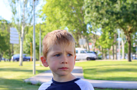 The blond boy frowns his eyebrows and looks seriously into the distance. A puzzled five-year-old boy.の写真素材