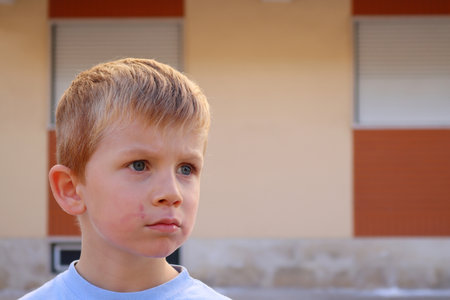 A blond boy with a dirty face stars intentionally into the distance. A tense five-year-old boy.の写真素材