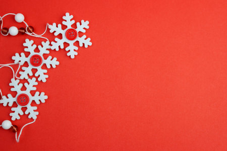 White felt snowflakes with red buttons in the middle on a bright red paper background. The concept of Christmas and New Year's Eve.の写真素材