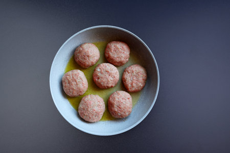Raw meat cutlets in a large round pan on a gray background. Frying cutlets.の写真素材