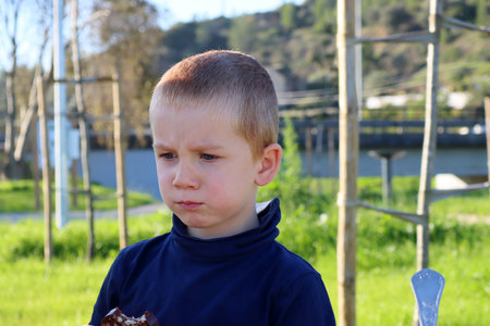The short-haired, blond boy puffed out his cheeks and lowered his eyes. A frowning five-year-old boy.の写真素材