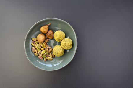 Energy balls from pistachios and dried figs in a round bowl on a gray background. A simple and healthy snack.の写真素材