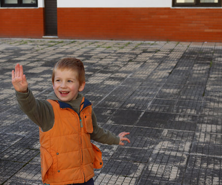 The blond boy smiles and extends his hand forward. A joyful five year old boy.の写真素材