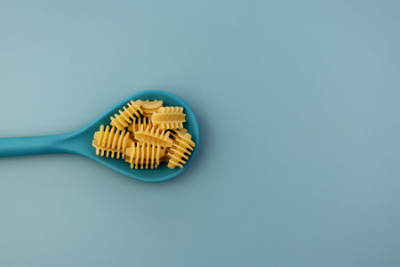 Pasta radiator in a blue spoon on a blue background.の写真素材