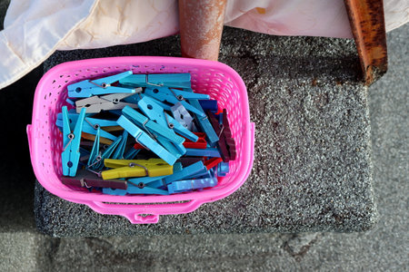 Blue clothes pins in a pink plastic basket.の写真素材
