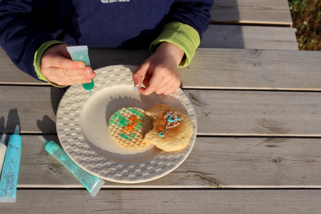 Child's hands decorate cookies with edible paints. view from above.の写真素材