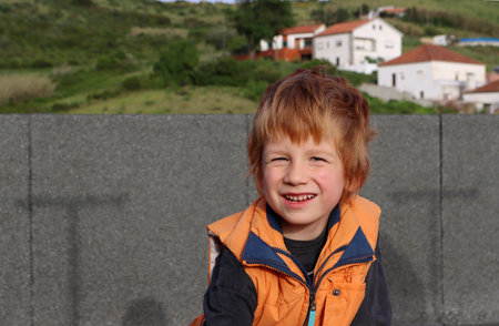 The blond boy narrows his eyes and looks straight into the camera. Happy five year old boy.の写真素材
