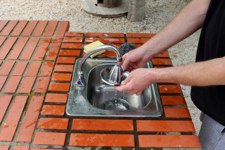 Men's hands wash a manual juicer in the sink in an outdoor kitchen.の写真素材