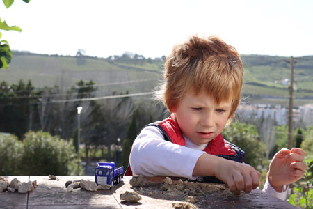 The blond boy enthusiastically plays with the sand.の写真素材