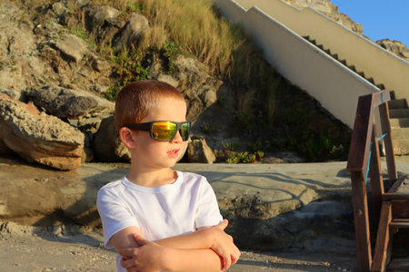 A blond boy in sunglasses looks at the Atlantic Ocean.の写真素材