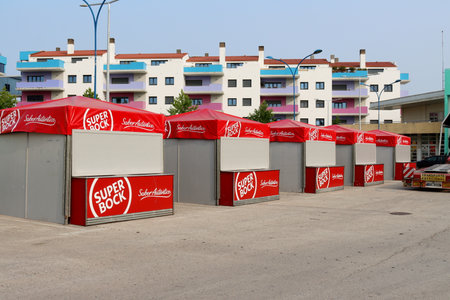 Torres Vedras, Portugal - June 27, 2023: Five Red Super Bock tents stand in a row on the street, against the backdrop of a house with colorful balconies.のeditorial素材