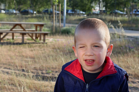 A blond boy with a dirty chin narrows his eyes and looks into the distance. Joyful six year old boy.の写真素材