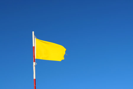Yellow flag waving in the wind on a background of blue sky. Flags on the beach.の写真素材