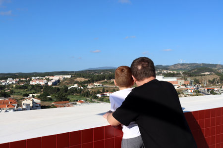 Father and son look at the city from above together. Man and child from the back.の写真素材
