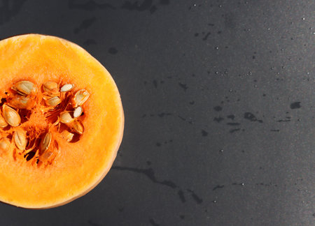 Ripe round pumpkin in a section on a black background, top view, copy spaceの写真素材