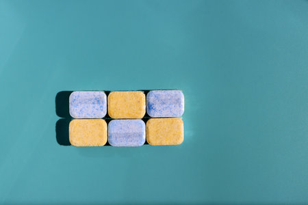 Blue and yellow dishwasher tablets on blue backgroundの写真素材