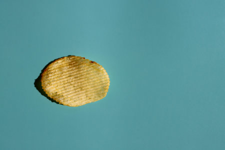 Crispy golden potato chips isolated on blue background. View from above. Copy space.