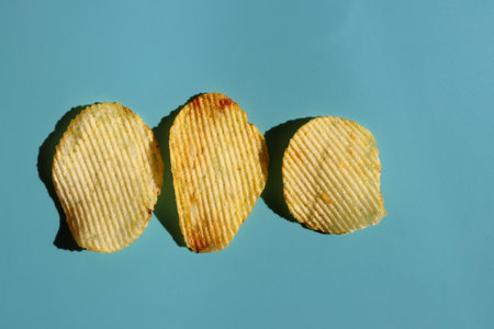 Three slices of ribbed Potato chips on a blue background, close-up, top viewの写真素材