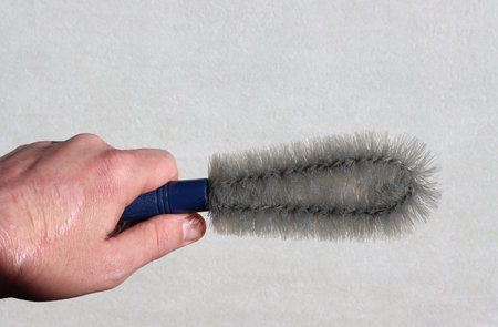 Close-up of a hand holding a semicircular brush for removing dust and cobwebs.の写真素材