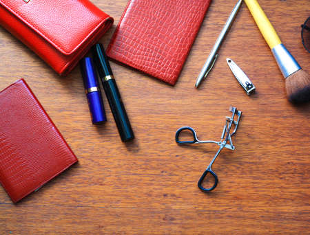 Women's things on the table, documents, cosmetics, brush, pen, eyelash curlers, top viewの写真素材