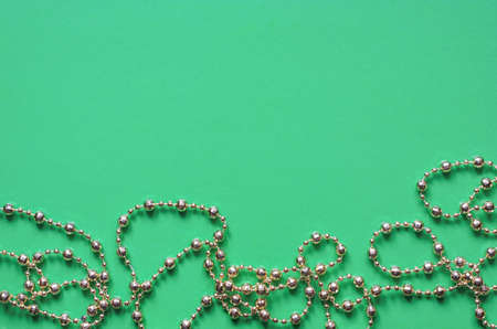 Christmas garland beads in gold on a green background top view copyspaceの写真素材