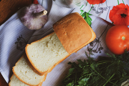 Bread with cut pieces on a napkin tomatoes herbs and garlic top view