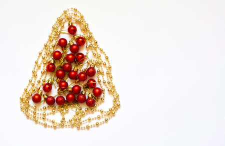 Christmas tree flat lay made of gold beads and red Christmas balls on white backgroundの写真素材