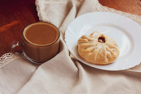 Sweet Breakfast coffee with milk and a bun on a napkin on the tableの写真素材