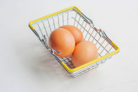 Three brown eggs in a grocery basket