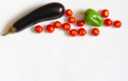 Flat lay food on a white background eggplant red cherry tomatoes and green bell pepper copy spaceの写真素材