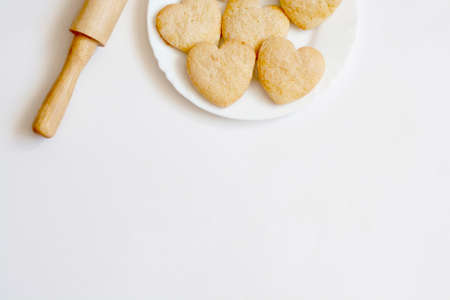Shortbread cookies in the shape of hearts on a white plate and rolling pin top view copy spaceの写真素材