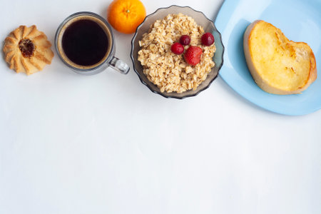 Breakfast oatmeal with berries coffee tangerine and pastries flat lay copy spaceの写真素材